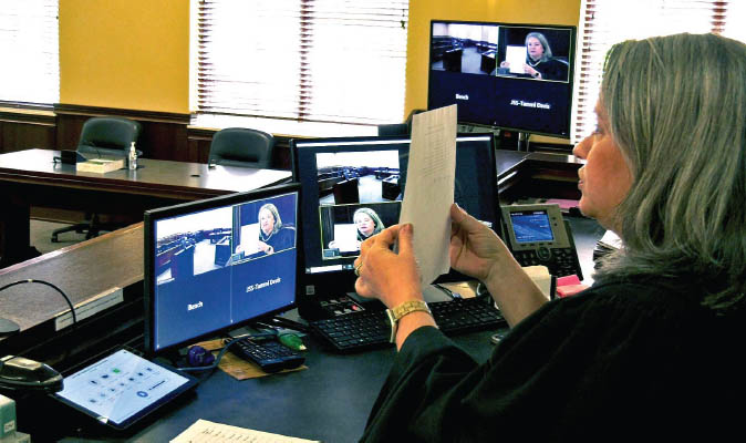 hybrid court hybrid courtroom image, judge holding document up to court proceeding